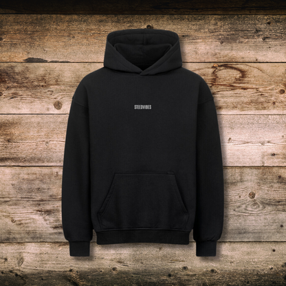 Oversized Damen-Hoodie TRUST in Schwarz vorne auf Holz
